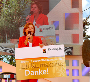 Ministerpräsidentin Malu Dreyer präsentiert eine übergroße, symbolische Jubiläums-Ehrenamtskarte